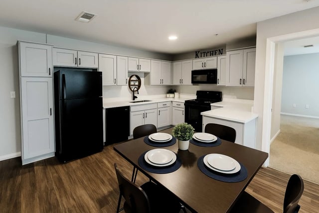 Kitchen with black refrigerator white cabinets dining table kitchen at Altitude Baton Rouge | Apartment Complex in Baton Rouge Student Accommodation