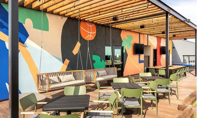 Swings and tables with green chairs outdoor lounge at The Dean Campustown in Champaign Student Accommodation