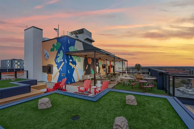 Rooftop deck with seating tables and mural playing area at The Dean Campustown in Champaign Student Accommodation