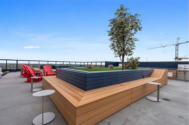 Rooftop patio with red chairs grill and tree outdoor area at The Dean Campustown in Champaign Student Accommodation