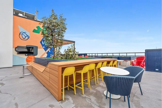 Rooftop bar with yellow stools blue chairs exterior at The Dean Campustown in Champaign Student Accommodation