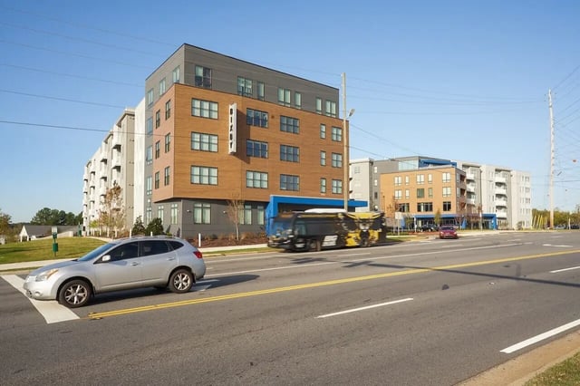 Modern apartment buildings with cars and bus exterior at Bixby Kennesaw in Kennesaw Student Accommodation
