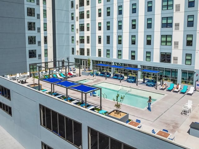 Pool lounge chairs tables and blue shades exterior at The Dean Reno in Reno Student Accommodation