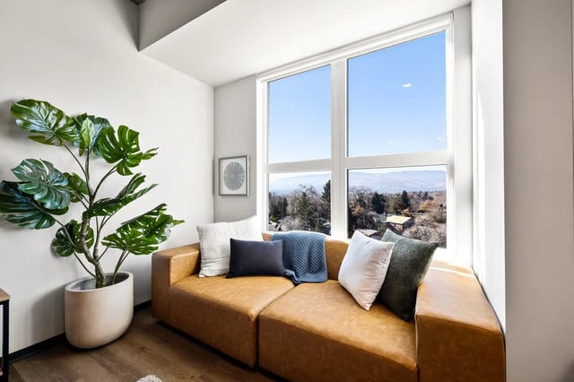 Brown sectional sofa with pillows and large plant living room at The Dean Reno in Reno Student Accommodation