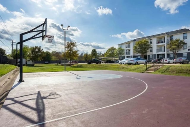 Basketball court with building and parking lot exterior at Crossing Place in College Station Student Accommodation