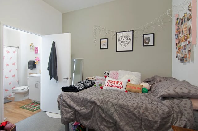 Bed with pillows and blankets bathroom visible bedroom at The Q'ube in Springfield Student Accommodation