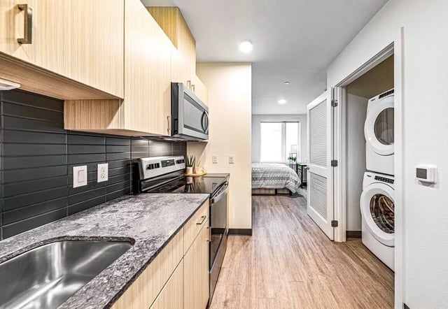 Modern kitchen with stacked washer dryer bedroom studio at Theory U District in Seattle Student Accommodation