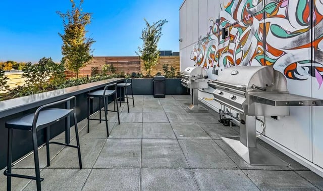 Two grills and bar stools on patio exterior at Theory U District in Seattle Student Accommodation