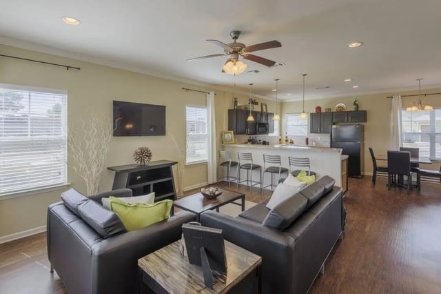 Dark leather sofas TV bar stools kitchen living room at Cobalt Row in Murfreesboro Student Accommodation