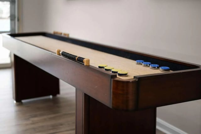 Wooden shuffleboard table with pucks playing area at The Gathering in Salisbury Student Accommodation
