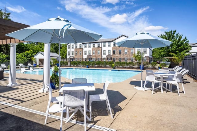Patio tables chairs umbrellas by swimming pool exterior at The Gathering in Salisbury Student Accommodation