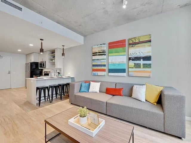 Gray sectional sofa with colorful pillows and kitchen living room at The James in Richmond Student Accommodation