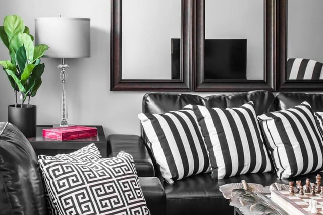Black leather sofa striped pillows living room at The George in Statesboro Student Accommodation