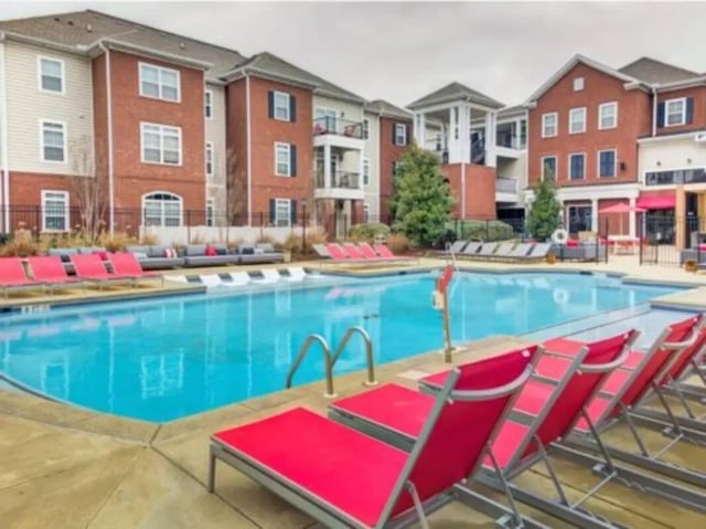 Pool with red loungers and apartment buildings exterior at East Edge in Tuscaloosa Student Accommodation