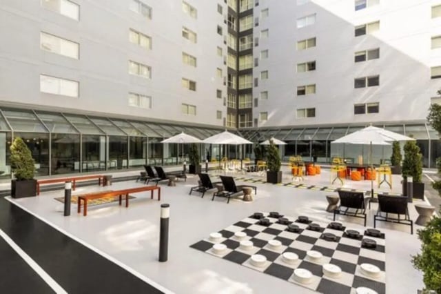 Outdoor courtyard with checkers lounge chairs umbrellas exterior at The Quad On Delaware in Minneapolis Student Accommodation