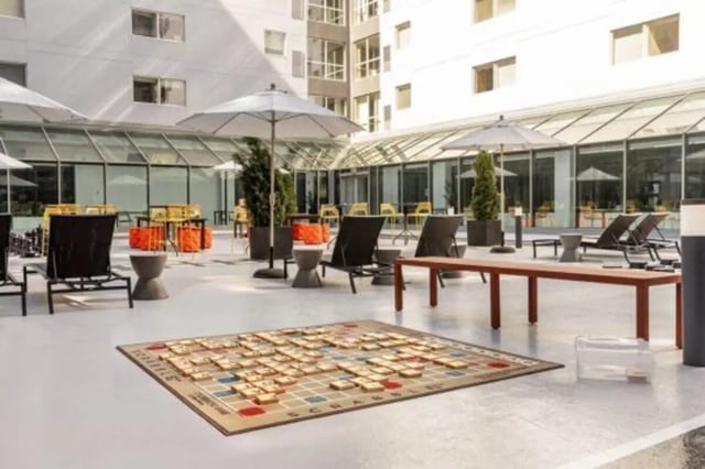 Outdoor Scrabble board lounge chairs umbrellas exterior at The Quad On Delaware in Minneapolis Student Accommodation