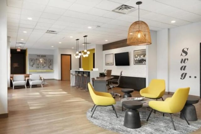 Modern lounge with yellow chairs and tables living room at The Quad On Delaware in Minneapolis Student Accommodation