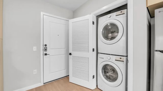 Stacked white washer dryer next to door Laundry room at The Sinclair in Austin Student Accommodation