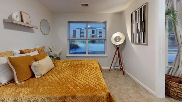 Bed with yellow quilt and pillows bedside lamp bedroom at Block20