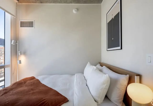 Bed with white linens and brown blanket Bedroom at Straits Row in Chicago Student Accommodation