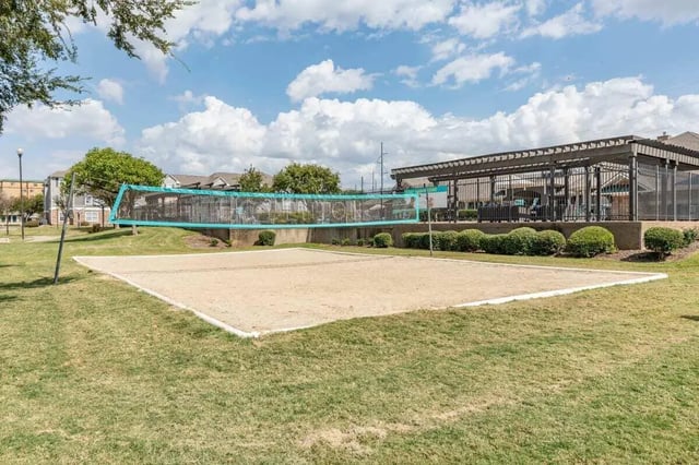 Sand volleyball court with net and seating area exterior at Astoria in Denton Student Accommodation