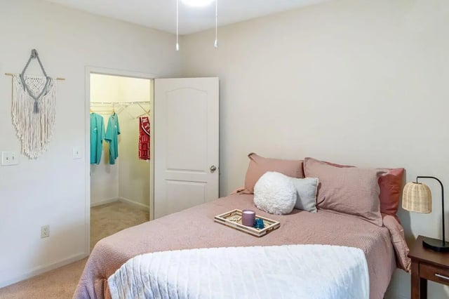 Bed with pillows closet with clothes bedroom at The Bluff at Waterworks Landing in Tuscaloosa Student Accommodation