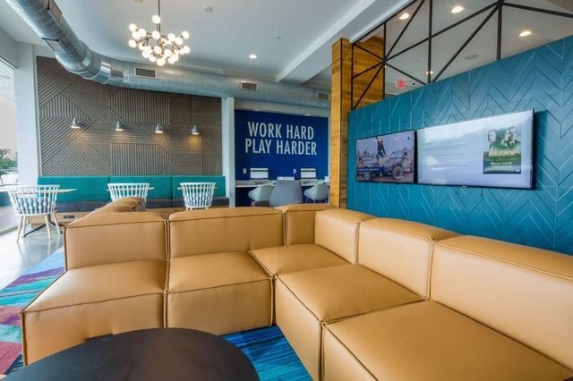 Large tan sectional sofa two TVs wall lounge at The Bluff at Waterworks Landing in Tuscaloosa Student Accommodation