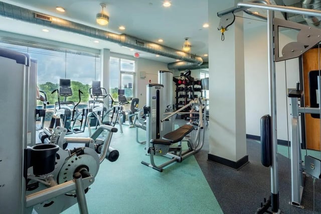 Gym equipment with large windows fitness room at The Bluff at Waterworks Landing in Tuscaloosa Student Accommodation
