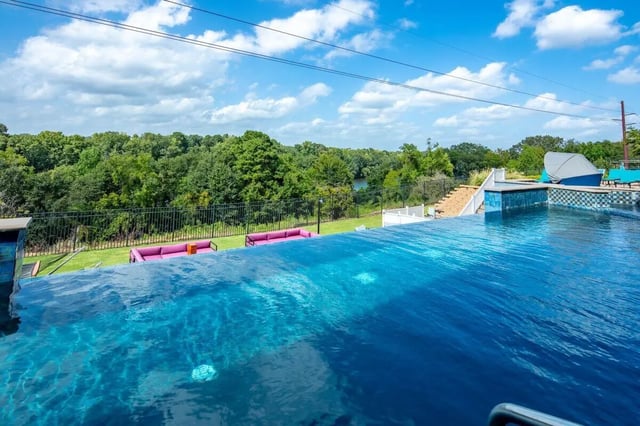 Infinity pool with pink couches green lawn exterior at The Bluff at Waterworks Landing in Tuscaloosa Student Accommodation