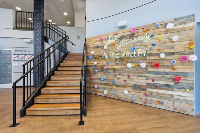 Wooden stairs neon sign wall with flowers lobby at The Valley Apartments & Townhomes in State College Student Accommodation