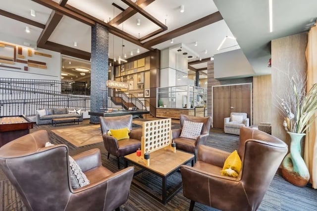 Leather chairs connect four game and shuffleboard table living room at The Valley Apartments & Townhomes in State College Student Accommodation