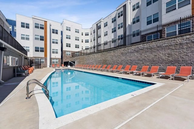 Swimming pool with orange lounge chairs exterior at The Valley Apartments & Townhomes in State College Student Accommodation