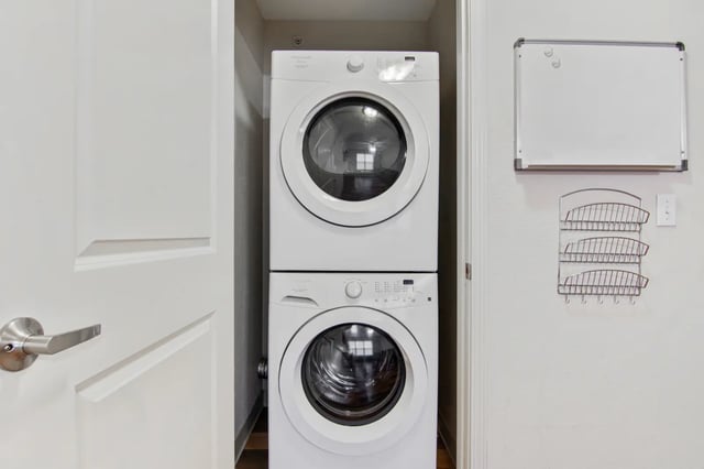 Stacked washer dryer with metal rack and whiteboard laundry area at The Jefferson Apartments in Springfield Student Accommodation