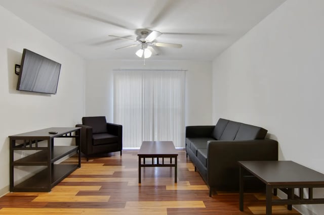 Black sofa armchair coffee table TV living room at The Jefferson Apartments in Springfield Student Accommodation