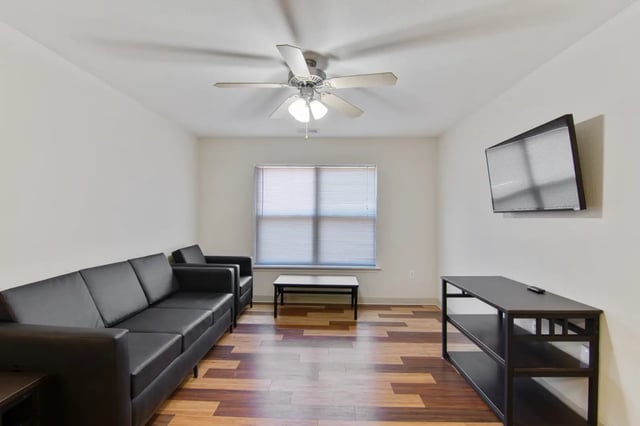 Black sofas coffee table and TV living room at The Jefferson Apartments in Springfield Student Accommodation