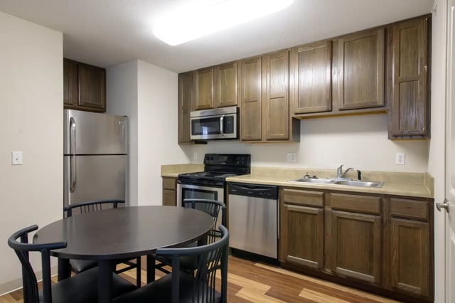 Dining table chairs refrigerator microwave stove sink kitchen at The Jefferson Apartments in Springfield Student Accommodation