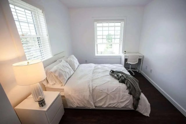 Bed with white bedding desk chair and lamp bedroom at Campus Prime in Syracuse Student Accommodation