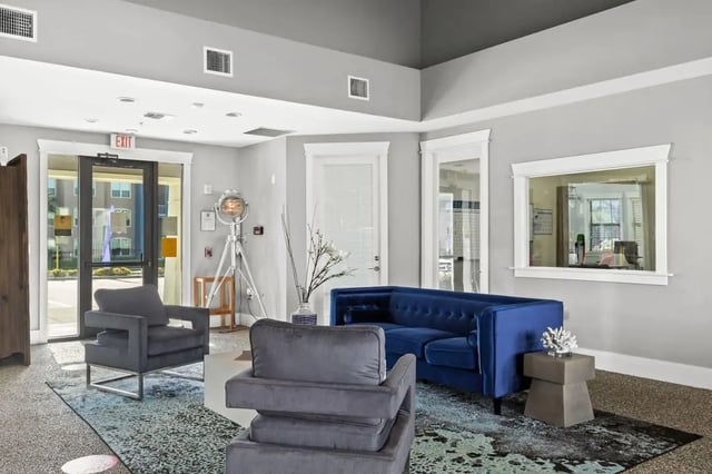 Blue sofa grey armchairs patterned rug living room at Campus Quarters in Corpus Christi Student Accommodation