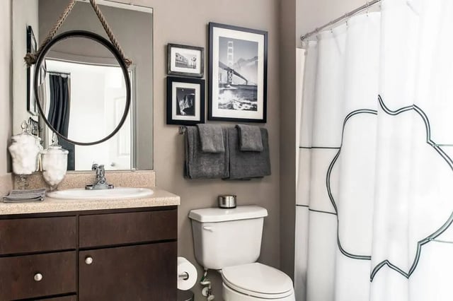 Sink toilet framed pictures towels shower curtain Bathroom at Campus Quarters in Corpus Christi Student Accommodation