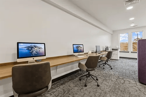 Computers on long desk with chairs study area at The Jolly Roger in Greenville Student Accommodation