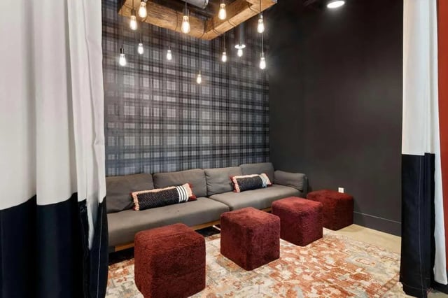 Gray sectional sofa with ottomans and plaid wallpaper living room at Atlas on 17th in Bloomington Student Accommodation