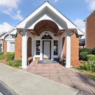 Brick building entrance with white columns and benches exterior at Eighteen18 at Southern in Statesboro Student Accommodation