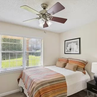 Bed with striped comforter and artwork bedroom at Eighteen18 at Southern in Statesboro Student Accommodation