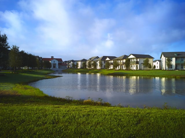Apartment buildings reflected in lake exterior at The Junction at College Station in College Station Student Accommodation