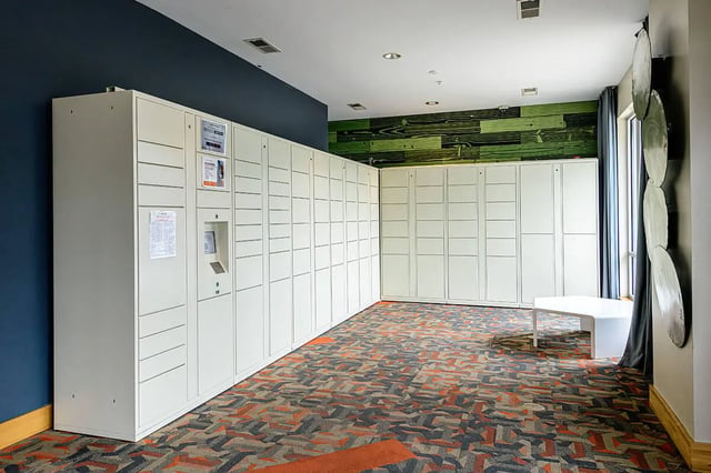 White lockers with touch screen and patterned carpet Lobby area at The Dillon in Bloomington Student Accommodation