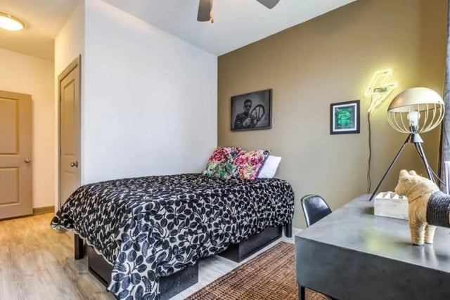 Bed with floral pillows desk and lamp bedroom at The Boundary At West End in Greenville Student Accommodation