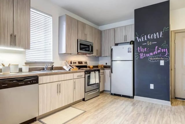 Modern kitchen with light wood cabinets and chalkboard wall kitchen at The Boundary At West End in Greenville Student Accommodation