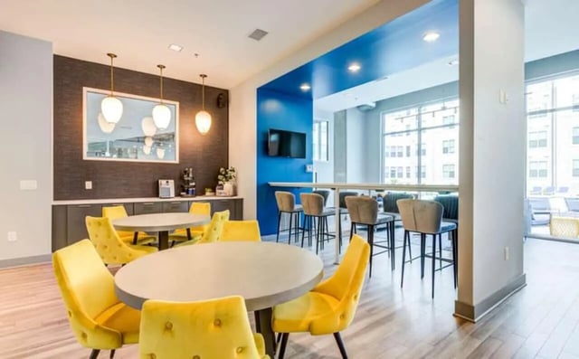 Round tables yellow chairs bar seating and TV communal area at The Boundary At West End in Greenville Student Accommodation