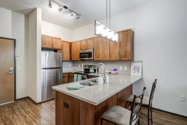 Modern kitchen with stainless steel appliances granite island and seating kitchen at The Knoll Dinkytown in Minneapolis Student Accommodation