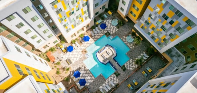 Courtyard with pool lounge chairs umbrellas and buildings exterior at Apollo Tempe in Tempe Student Accommodation